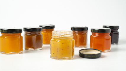 Different jam flavors on white background. Delicious jam in little jars. Set of different jams in glass jars.