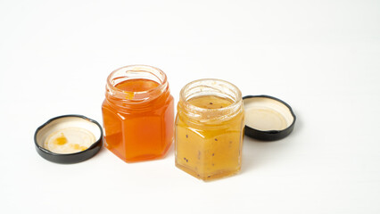 Little jam jars on white background. Small glass jars with passion fruit jam. Apricot marmalade. Coupe of jam jars