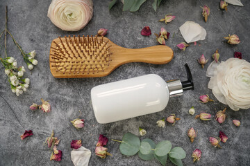 Fototapeta na wymiar Natural homemade shampoo or wash gel in white pump bottle on grey background with hairbrush, roses and eucalyptus. Natural skin care. 