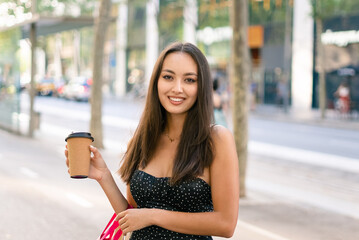 Cheerful female shopper with takeaway coffee