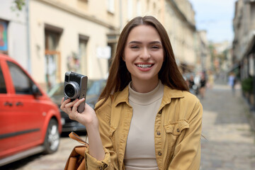 Young woman with camera on city street. Interesting hobby