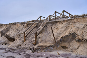 a damaged shoreline and broken stairs leading to the beach in the Hamptons
