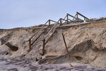 a damaged shoreline and broken stairs leading to the beach in the Hamptons
