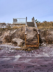 a damaged shoreline and broken stairs leading to the beach in the Hamptons