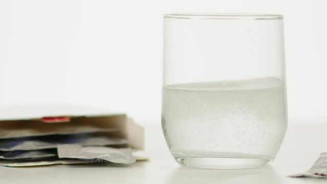 Comprim&eacute; d'aspirine effervescent dilu&eacute; dans un verre d'eau avec une boite &agrave; cot&eacute;