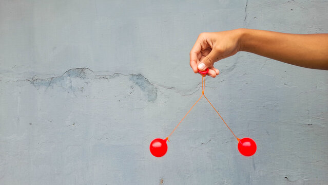 Kid holding lato-Lato. A traditional toy consisting of two heavy pendulums made of plastic and suspended by a string. Its  traditional game can be found in Indonesia. These lato-lato have been very ic