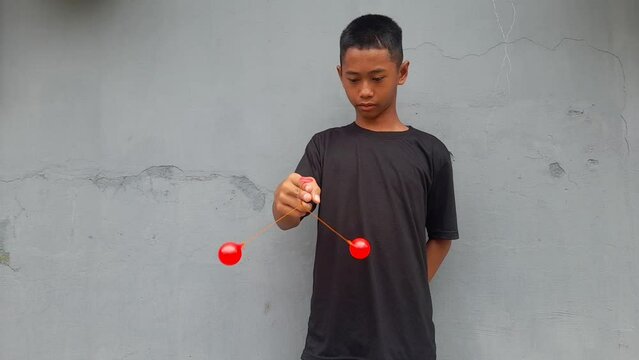 Kid holding lato-Lato. A traditional toy consisting of two heavy pendulums made of plastic and suspended by a string. Its  traditional game can be found in Indonesia. These lato-lato have been very ic
