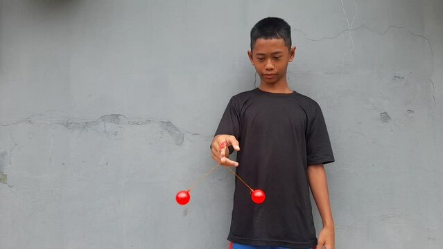 Kid holding lato-Lato. A traditional toy consisting of two heavy pendulums made of plastic and suspended by a string. Its  traditional game can be found in Indonesia. These lato-lato have been very ic