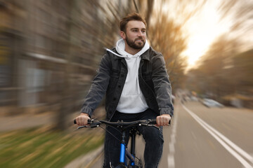 Fototapeta premium Happy handsome man riding bicycle in city, motion blur effect