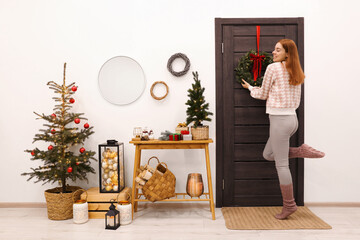Woman decorating her entry way for Christmas - obrazy, fototapety, plakaty