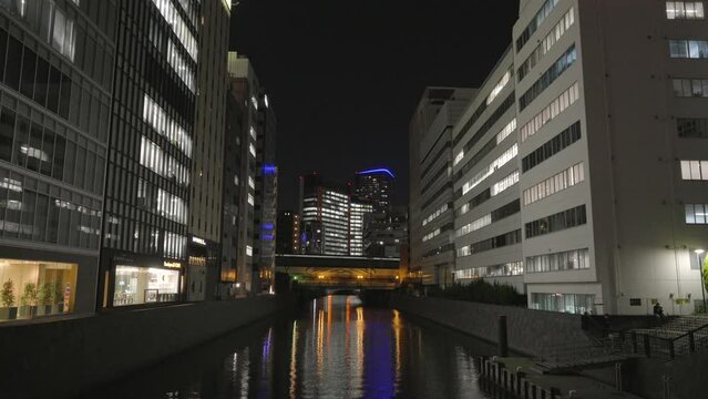 This video shows a Yokohama canal cityscape at night with a train passing by in the distance.
