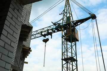 Construction site with tower crane under beautiful cloudy sky, low angle view