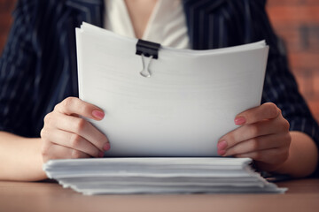 Woman stacking documents at wooden table in office, closeup