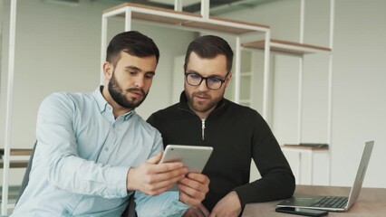Young male employee shows mentor his completed work on a tablet, Praise from supervisor for a job well done