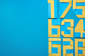Different numbers made of paper on light blue background, flat lay. Space for text