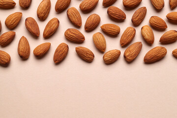 Delicious raw almonds on beige background, flat lay. Space for text