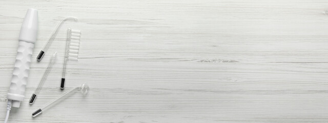 High frequency darsonval device and different nozzles on white wooden background, flat lay. Banner...