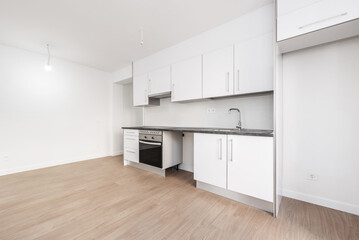 Conventional kitchen recently installed in an open way in a room with laminated floors in which all the appliances have not yet been installed