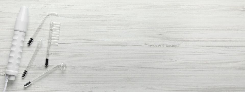 High frequency darsonval device and different nozzles on white wooden background, flat lay. Banner design with space for text