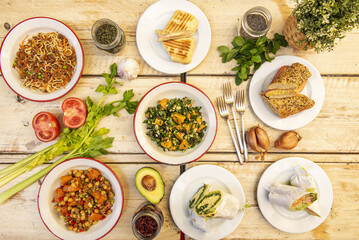 Healthy food snacks and plates set with vegan salads, snacks with spinach and seeds and lots of fresh fruits and vegetables