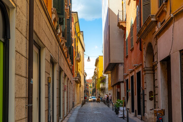 Fototapeta na wymiar A narrow street of shops and cafes in the historic medieval old town center of Verona, Italy. 
