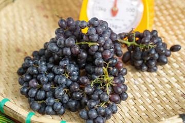 A bunch of seedless grapes in bamboo baskets that farmers sell at the market. soft and selective focus.    