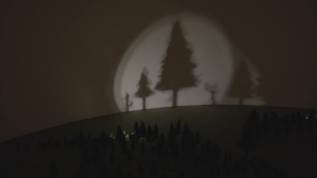 This video shows a surreal shadow puppet show of forest trees and nature.