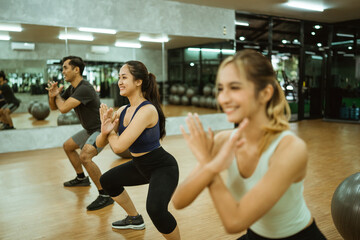 Fototapeta na wymiar asian woman doing squat stance and hand defense with her friend during workout at fitness center