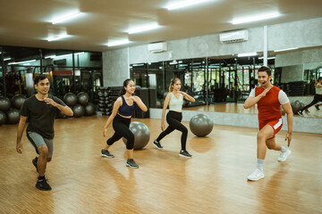 Fototapeta na wymiar group of sporty men and women doing squats during exercise with instructor in fitness center