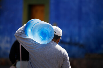 Man carrying a water gallon on his shoulder. Water delivery worker