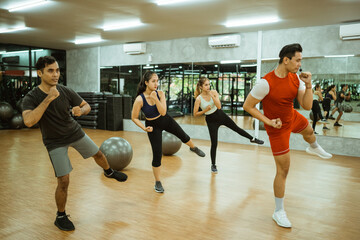 instructor and some sporty people doing inner thigh muscle exercises during group exercises in the fitness center