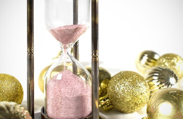 sparkling holiday image with hourglass and gold christmas ornaments on white ground