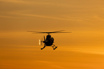 Fototapeta na wymiar Tourist helicopter flying in the sky at sunset.