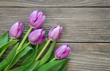 Bouquet of purple tulips on a wooden surface, fresh spring flowers, top view, copy space.