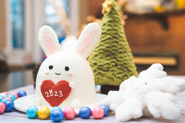 white rabbit shape cake with tree, snow flake and colorful balls decoration to celebrate year 2023