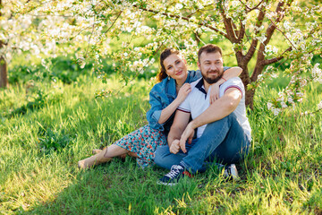 Fototapeta premium a man and a woman on a lawn in a blooming spring garden. 