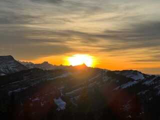 Magical sunset and shy sun behind winter clouds over the Obertoggenburg region and in the Swiss Prealps, Urnäsch (Urnaesch or Urnasch) - Canton of Appenzell Innerrhoden, Switzerland (Schweiz)