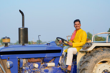 Indian farmer sitting on tractor at agriculture field.