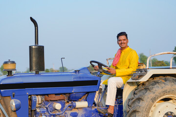 Indian farmer sitting on tractor at agriculture field.