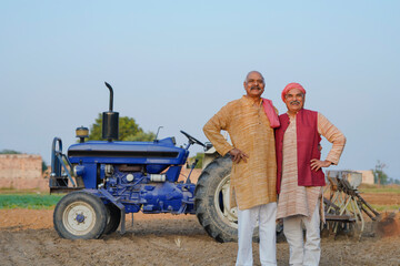 Obraz premium Two indian farmer standing near new tractor at agriculture field.