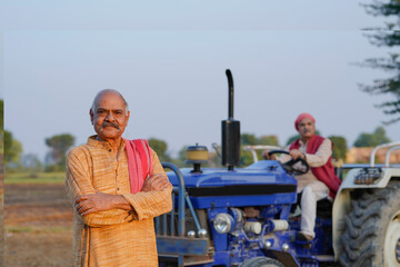 Two indian farmer standing near new tractor at agriculture field.