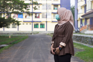 Woman in hijab wears medical mask standing to protect her from air pollution, transmissible infectious diseases or virus