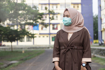 Fototapeta na wymiar Woman in hijab wears medical mask standing to protect her from air pollution, transmissible infectious diseases and virus