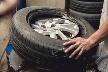 A man removing a tire from the rim after using a tire bead breaker at a vulcanizing shop.