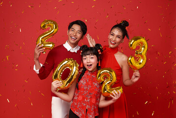 Happy asian family in red casual attire showing number 2023 greeting happy new year with smiles on...