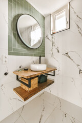 a modern bathroom with marble tiles and green tile walls, including a round mirror on the wall...