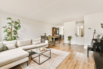a living room with a piano in the corner and an open door leading into the dining area on the right...