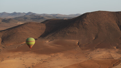 hot air balloon flying over the stone desert in Marrakesh with mountains in the background - Powered by Adobe