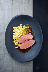 Tafelspitz Braten vom Kalb mit schwäbischen Spätzle serviert mit Dunkelbier Sauce als Draufsicht in einem Design Teller mit Textfreiraum  