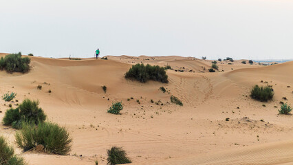 Fototapeta na wymiar Young boy walks around sand dunes in the desert. People